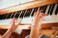 Girl is playing piano at home, high angle view, blurry background