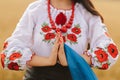 Young girl prays in the wheat field wearing Ukrainian national embroidered shirt with flower red wreath and holds flag at sunset y Royalty Free Stock Photo