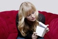 Young girl with present box on red sofa Royalty Free Stock Photo