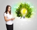 Young girl presenting idea light bulb with green tree Royalty Free Stock Photo