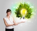 Young girl presenting idea light bulb with green tree Royalty Free Stock Photo