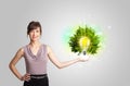 Young girl presenting idea light bulb with green tree Royalty Free Stock Photo