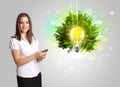 Young girl presenting idea light bulb with green tree Royalty Free Stock Photo