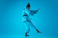 Young girl professional judoist isolated on blue studio background in neon light. Healthy lifestyle, sport concept. Royalty Free Stock Photo