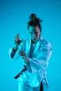 Young girl professional judoist isolated on blue studio background in neon light. Healthy lifestyle, sport concept. Royalty Free Stock Photo