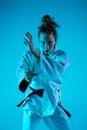 Young girl professional judoist isolated on blue studio background in neon light. Healthy lifestyle, sport concept. Royalty Free Stock Photo