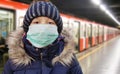 Young girl in protective sterile medical mask on her face looking at camera on tube station, virus, Chinese pandemic coronavirus