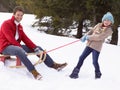 Young Girl Pulling Father Through Snow On Sled