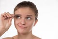 Young girl pulls out her eyebrows with tweezers metal on a white background Royalty Free Stock Photo