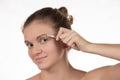 Young girl pulls out her eyebrows with tweezers metal on a white Royalty Free Stock Photo