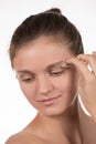 Young girl pulls out her eyebrows with tweezers metal on a white Royalty Free Stock Photo