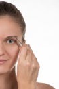 Young girl pulls out her eyebrows with tweezers metal on a white Royalty Free Stock Photo