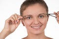 Young girl pulls out her eyebrows with tweezers metal on a white Royalty Free Stock Photo