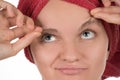 Young girl pulls out her eyebrows with tweezers metal on a white Royalty Free Stock Photo