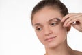 Young girl pulls out her eyebrows with tweezers metal on a white Royalty Free Stock Photo