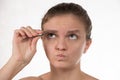 Young girl pulls out her eyebrows with tweezers metal on a white Royalty Free Stock Photo