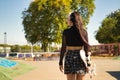 Young girl with punk style holding a skateboard with her hand walking backwards in a skateboard park Royalty Free Stock Photo