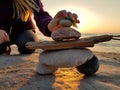 A young girl puts the final rock on an inuksuk inukshuk she& x27;s built at the beach at sunset 2