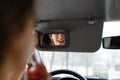 A young girl puts make-up in the car.