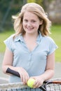 Young girl with racket on tennis court smiling Royalty Free Stock Photo