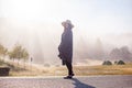 Young girl in a raincoat in the morning at dawn against a background of fog and mountains Royalty Free Stock Photo