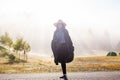 Young girl in a raincoat in the morning at dawn against a background of fog and mountains Royalty Free Stock Photo