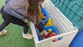 A young girl reaching into a toy storage box full of sports equipment Royalty Free Stock Photo