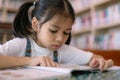 A young girl is reading a book in a library Royalty Free Stock Photo