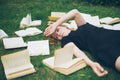 Young girl reading a book while lying in the grass. A girl among the books in the summer garden Royalty Free Stock Photo