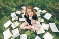 Young girl reading a book while lying in the grass. A girl among the books in the summer garden Royalty Free Stock Photo