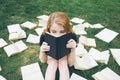 Young girl reading a book while lying in the grass. A girl among the books in the summer garden Royalty Free Stock Photo