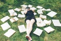 Young girl reading a book while lying in the grass. A girl among the books in the summer garden Royalty Free Stock Photo