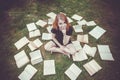 Young girl reading a book while lying in the grass. A girl among the books in the summer garden Royalty Free Stock Photo