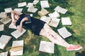 Young girl reading a book while lying in the grass. A girl among the books in the summer garden Royalty Free Stock Photo