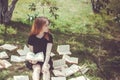 Young girl reading a book while lying in the grass. A girl among the books in the summer garden Royalty Free Stock Photo