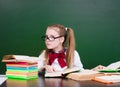 Young girl reading a book near empty green chalkboard Royalty Free Stock Photo