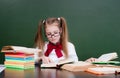 Young girl reading a book near empty green chalkboard Royalty Free Stock Photo