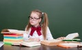 Young girl reading a book near empty green chalkboard Royalty Free Stock Photo