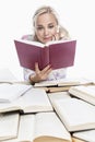 A young girl is reading. A smiling blonde with ponytails on her head sits at a table with books. Knowledge and education. Back to Royalty Free Stock Photo