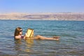 Young girl reads a book floating in the Dead Sea in Israel