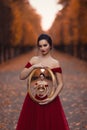 A young girl in a red ball gown holding in her hands a mirror in a vintage frame that reflects herself an infinite number of times