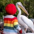 Girl in red beret interacts with colourful pelican with long beak in St James\'s Park, London UK.