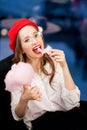 Young girl in red beret and glasses eats pink candy floss in France cafe Royalty Free Stock Photo