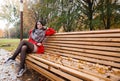 Young girl in a red coat sitting on a bench in a city park Royalty Free Stock Photo