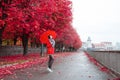 Young girl in a red coat with an umbrella standing on the alley of the park Royalty Free Stock Photo