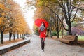 Young girl in a red coat with an umbrella walking on the alley Royalty Free Stock Photo