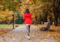 Young girl in a red coat walking on the alley Royalty Free Stock Photo