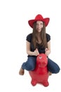 Young girl with red cowboy hat riding o toy horse Royalty Free Stock Photo