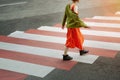 Young girl in red dress and green jacket crosses the road at a pedestrian crossing. Royalty Free Stock Photo