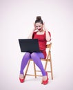Young girl in red dress sits on a chair and looks in horror at a laptop. Fear concept